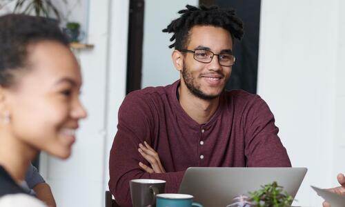 Man and woman smiling at someone across the table. 
