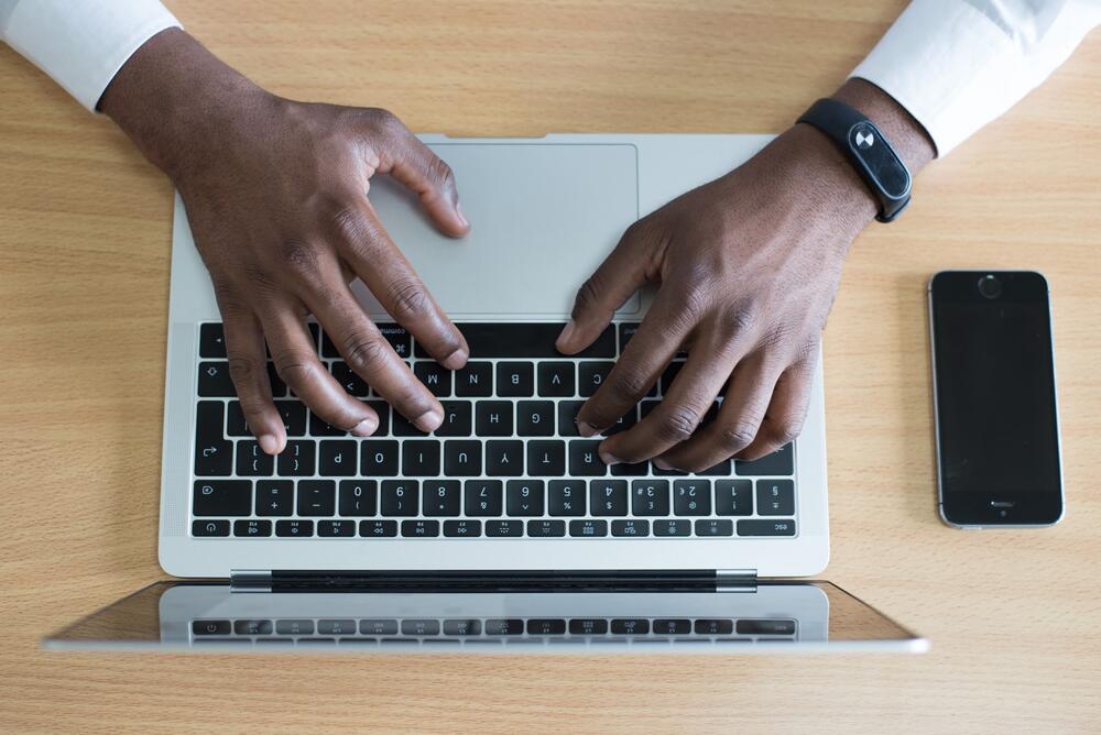 Worker's hands typing on a laptop in office attire