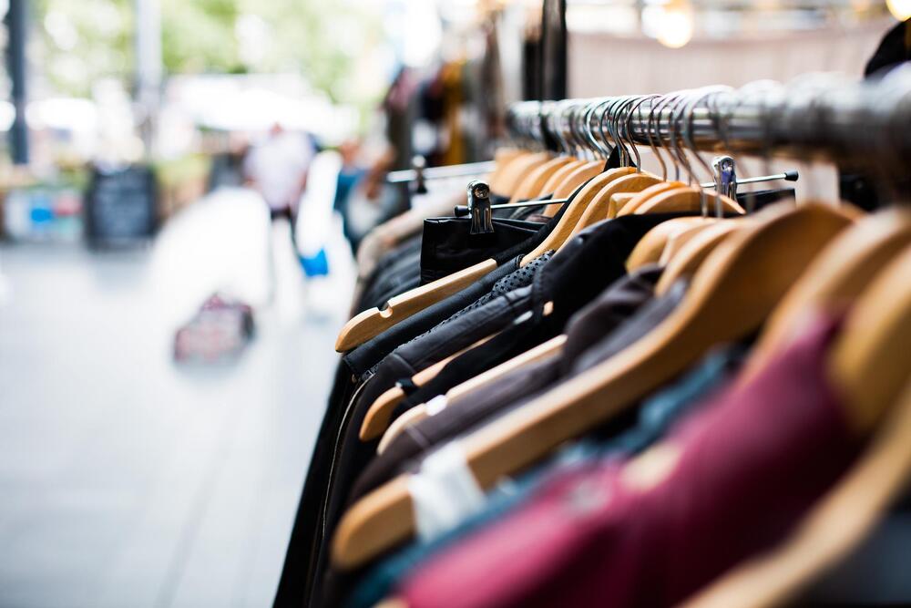 Rack of clothing on an outdoor sidewalk by a storefront