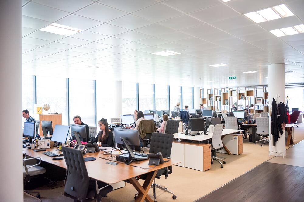 Team of employees working at a customer service call center in a bright and sunny room