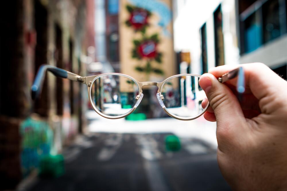 A hand holding glasses up to a city landscape
